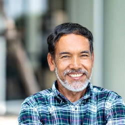 Man in plaid shirt smiling with arms crossed