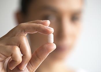 Hand holding a white antibiotic pill