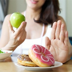 person choosing to eat apples instead of donuts
