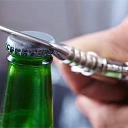 green glass bottle being opened with a bottle opener