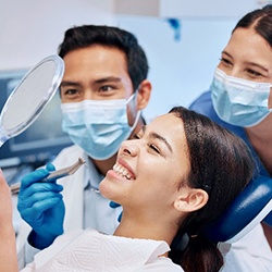 Dentist, dental assistant, and patient smiling at reflection