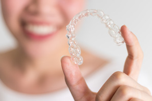 Close-up of a woman holding an Invisalign aligner
